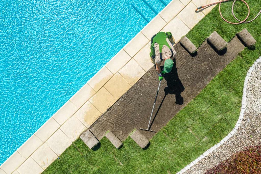 landscaper laying artificial grass by plunge pool