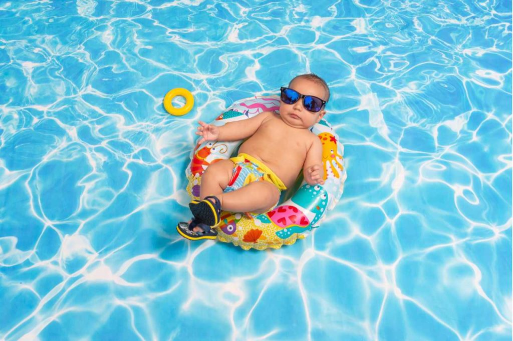 baby wearing sunglasses and swimming in floaty on a chill day in plunge pool