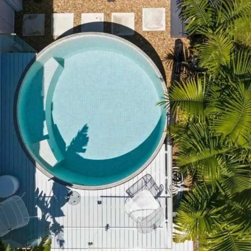 Top view of circular above ground plunge pool with timber deck and tropical landscaping in Grange backyard