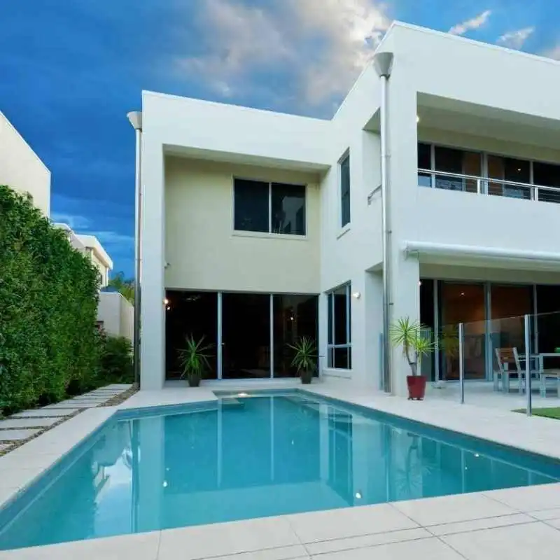 Custom concrete plunge pool beside a modern two-storey home with clean white exterior