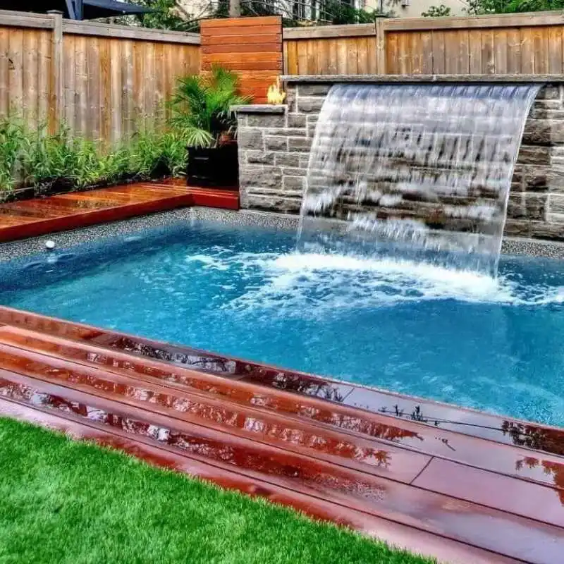 Rectangular plunge pool with stone waterfall feature and timber decking in modern Grange outdoor space