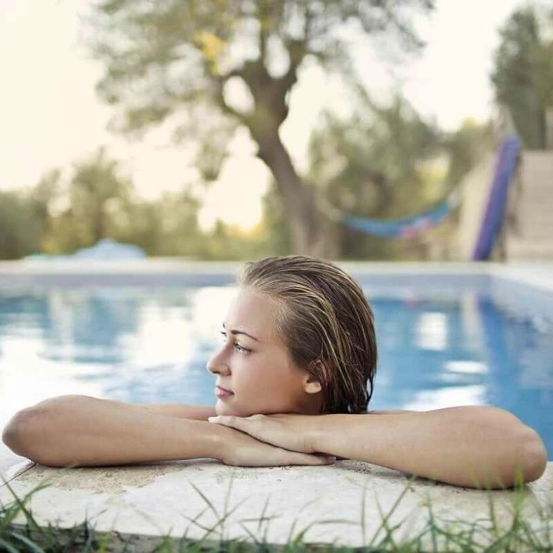 Woman relaxing at the edge of a residential plunge pool during daytime