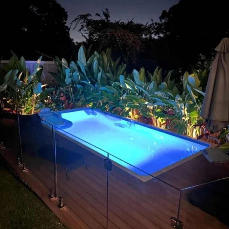 Precast concrete plunge pool with integrated seating and night lighting in landscaped Grange yard